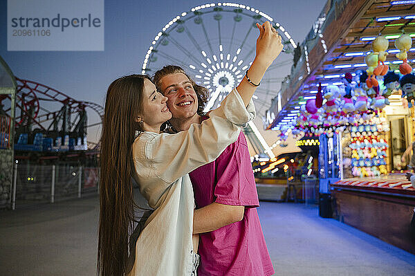 Cheerful couple taking selfie in amusement park