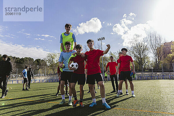 Soccer players standing together on field under sky