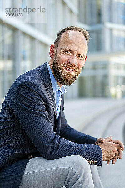 Serene businessman sitting in front of modern office building