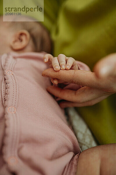 Hand of newborn baby holding mother's finger