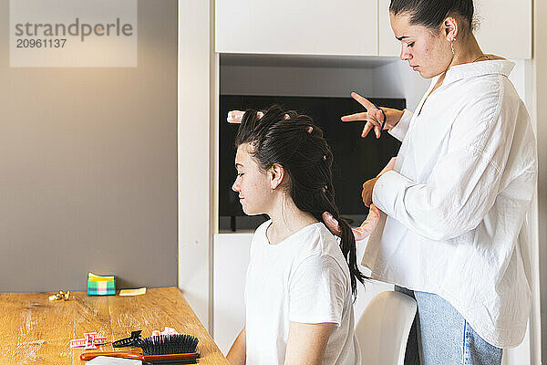 Woman using flexi curler to style girl's hair at home