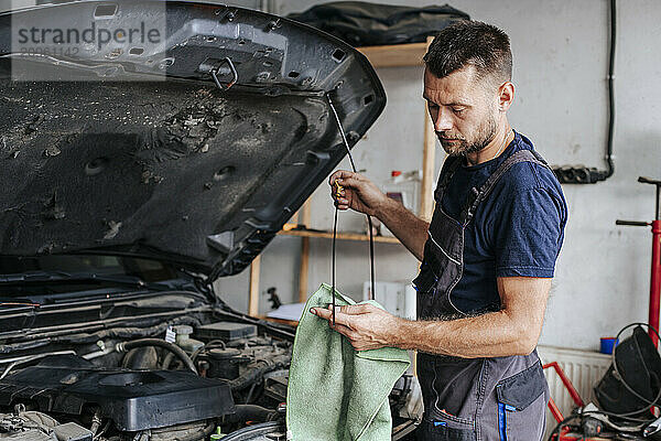 Auto mechanic using rag to repair car in garage