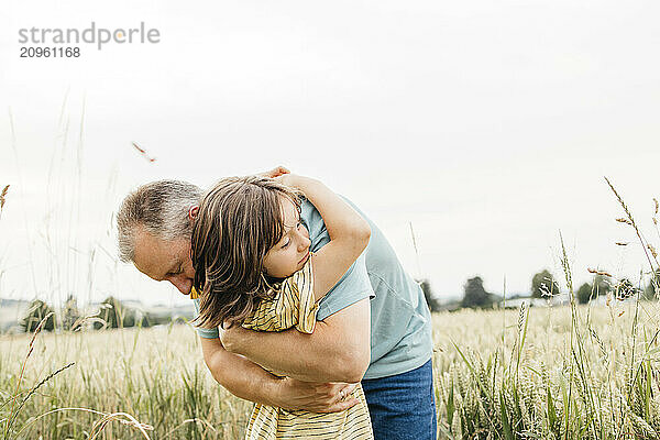 Father embracing son amidst agricultural field