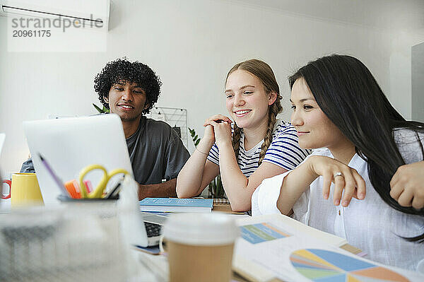 Multiracial friends studying on laptop at home