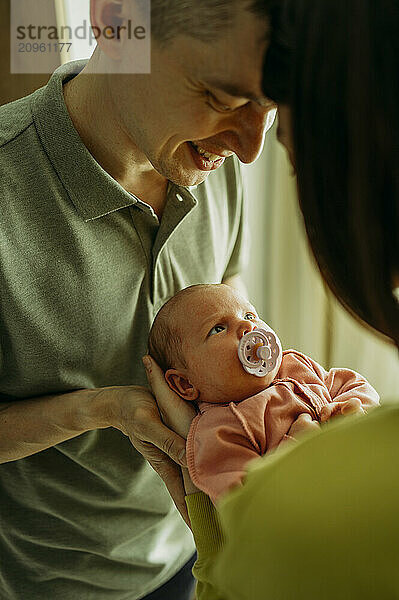 Happy man with baby girl sucking pacifier