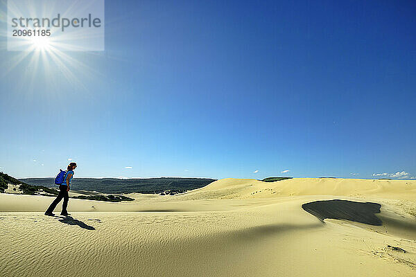 Woman walking on sand dunes under blue sky at sunny day in Eastern Cape  South Africa