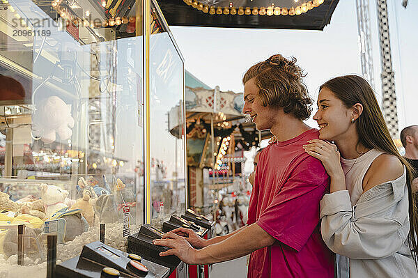 Couple playing grabbing game at amusement park