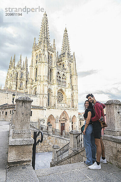 Smiling couple standing in front of Burgos Cathedral on vacation