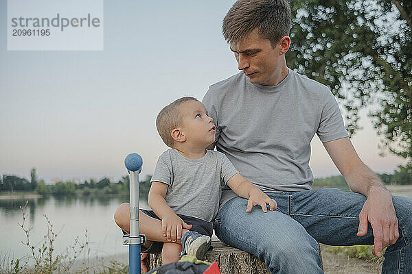 Father and son sitting together at park