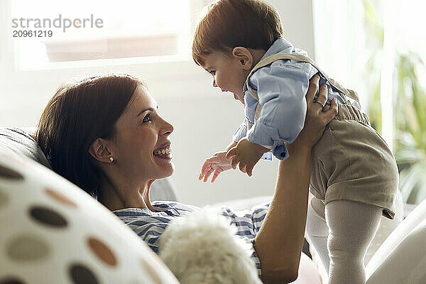 Happy young woman holding baby boy at home