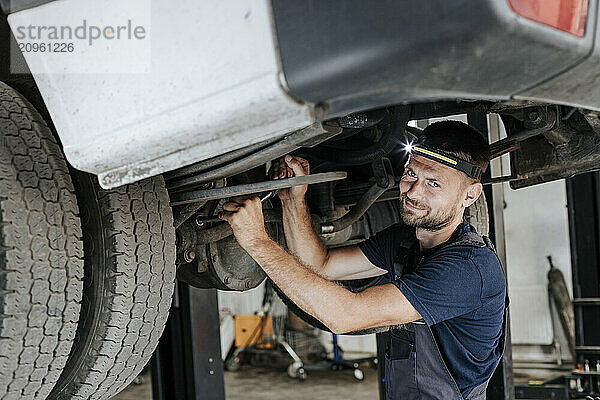 Mechanic replacing worn out parts on car inside garage