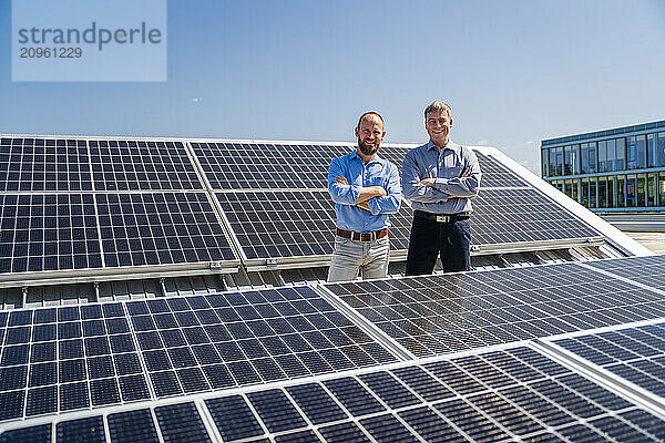 Two businessmen exude confidence as they stand among rows of solar panels  showcasing their commitment to renewable energy.