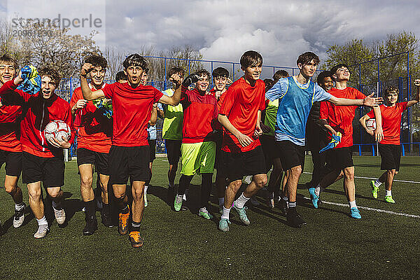 Cheerful soccer players winning match under cloudy sky