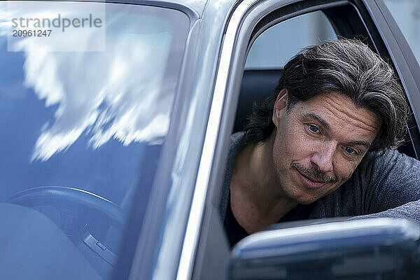 Smiling mature man looking out of car window