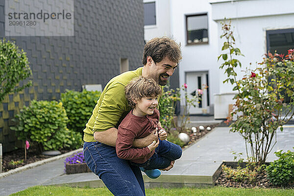 Happy father playing with son in back yard