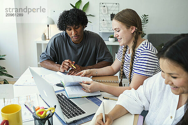 Happy multiracial friends doing project at home