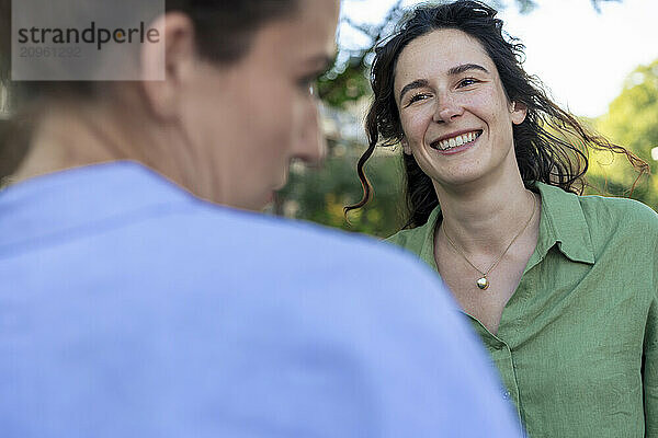 Smiling woman talking with friend at street