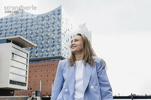 Happy businesswoman in blazer near Elbphilharmonie concert hall