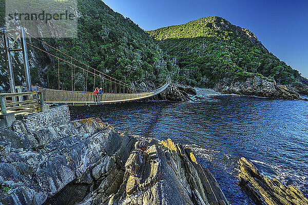 Travelers standing on suspension bridge over river at sunny day in Eastern Cape  South Africa