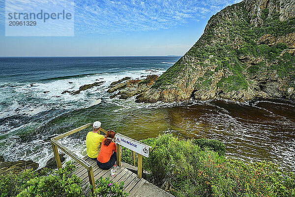 Hikers sitting on pier and looking at Bloukrans River in Tsitsikamma Section  Garden Route National Park  Eastern Cape  South Africa