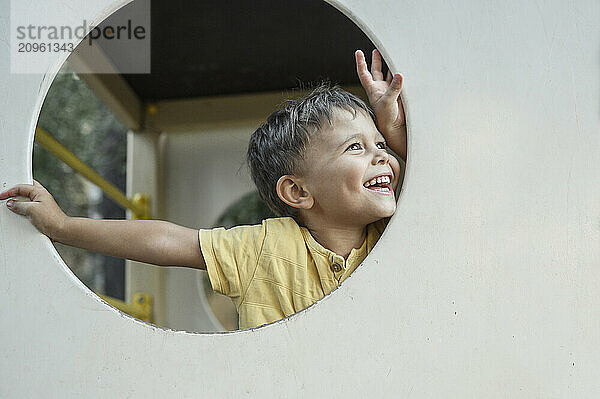 Smiling cute boy looking from playing equipment at playground