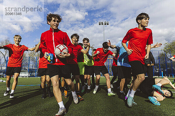 Happy soccer players running together on field