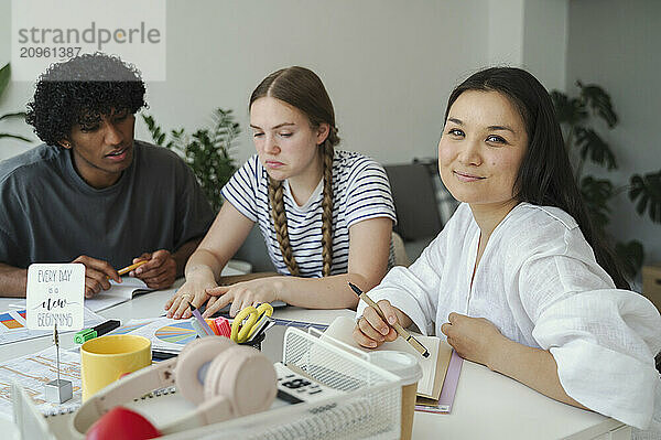 Smiling woman sitting and studying with friends at home