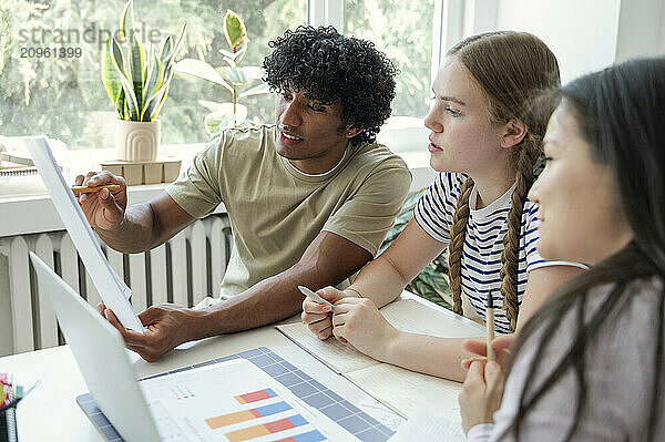 Curly haired man discussing with friends studying at home