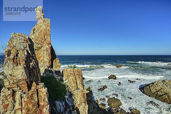 Rock spires near Indian Ocean under clear sky at Kranshoek Hiking Trail in Garden Route National Park  Western Cape  South Africa