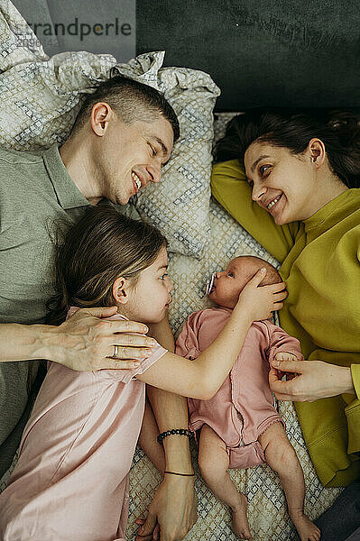 Happy parents lying with daughter's on bed