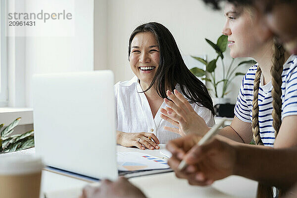 Cheerful university student studying with friends at home