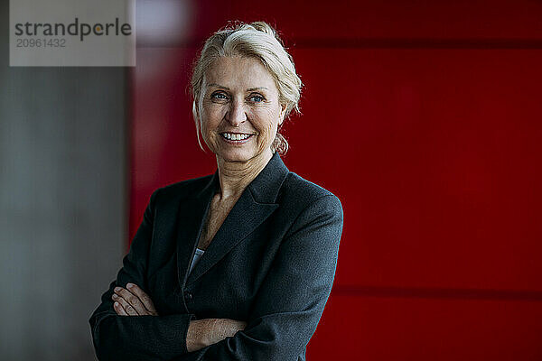 Smiling businesswoman with arms crossed at office