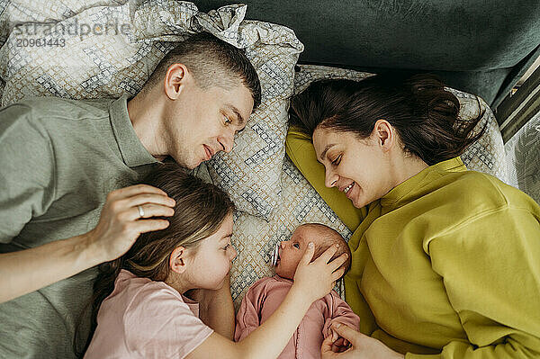 Happy family spending leisure time lying on bed