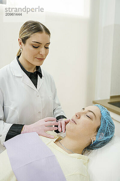 Dermatologist injecting dermal filler to patient in clinic