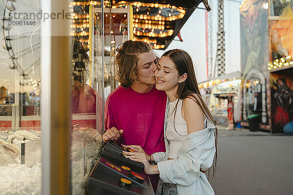 Happy couple playing toy grabbing game in amusement park