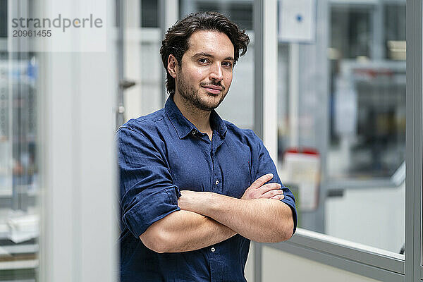 Confident businessman with arms crossed in factory