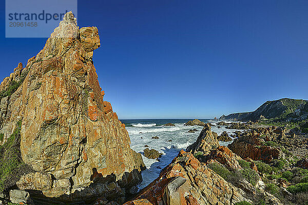 Rock spires in Indian Ocean under blue sky at Garden Route National Park  Western Cape  South Africa