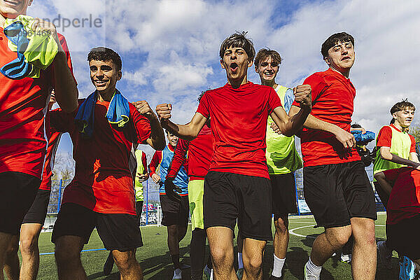 Cheerful soccer team winning match under cloudy sky