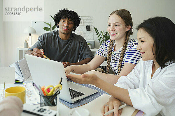 Students discussing and studying on laptop at home