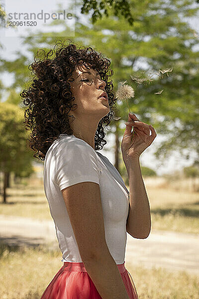 Woman blowing dandelion at park