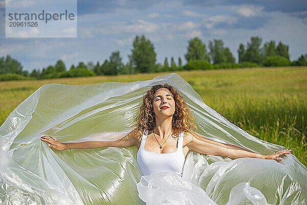 Happy young woman with arms outstretched standing at field