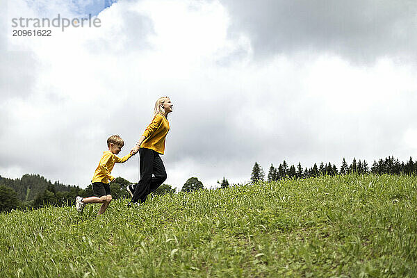 Brother and sister holding hands and running uphill