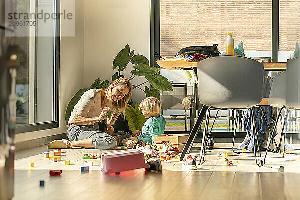 Mother spending leisure time playing building blocks with son at home