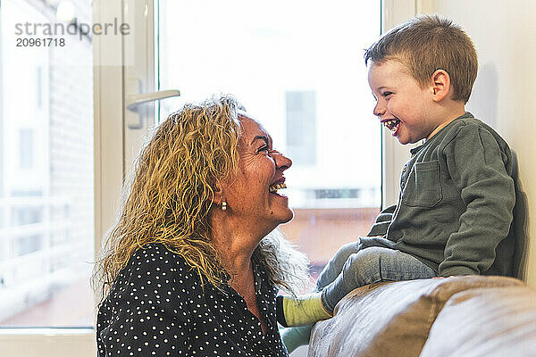 Grandmother spending leisure time with grandson sitting at home