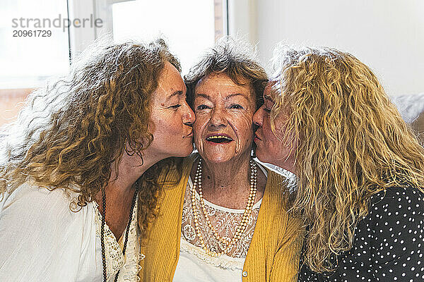 Daughters kissing mother at home