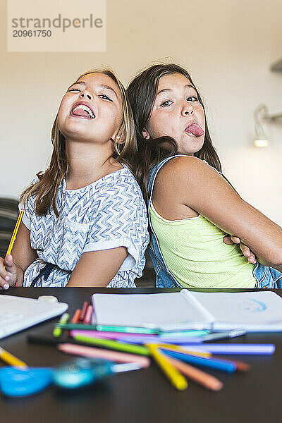 Friends playfully sticking out tongue at home