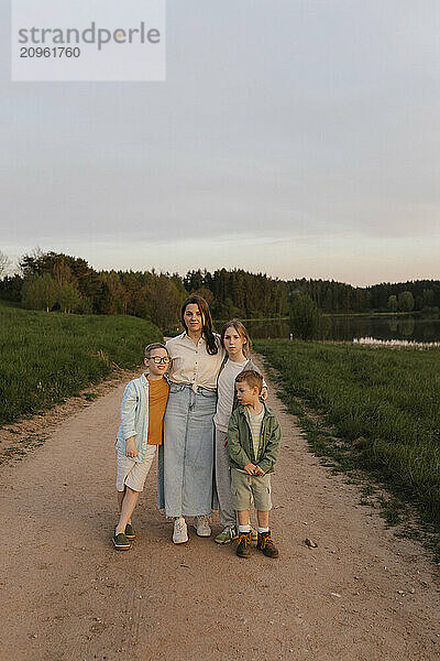 Smiling mother with children standing on dirt road