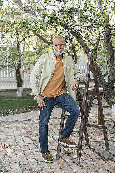 Smiling man standing by ladder in back yard