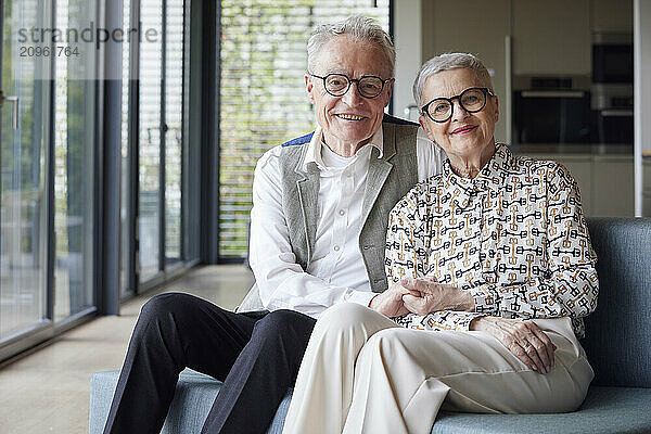 Portrait of happy senior couple sitting on couch at home