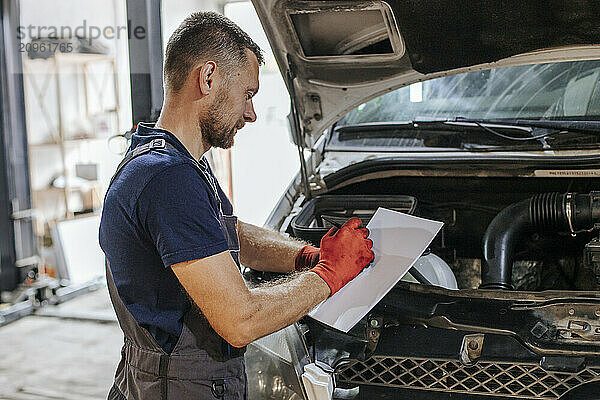 Auto mechanic writing on paper in garage